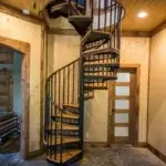 steel spiral staircase with decorative risers and wood treads down to finished basement