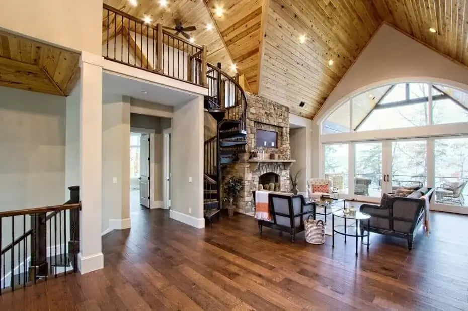 forged iron spiral staircase with solid wood handrail and treads leading to a loft in living room of timberframe mountain house